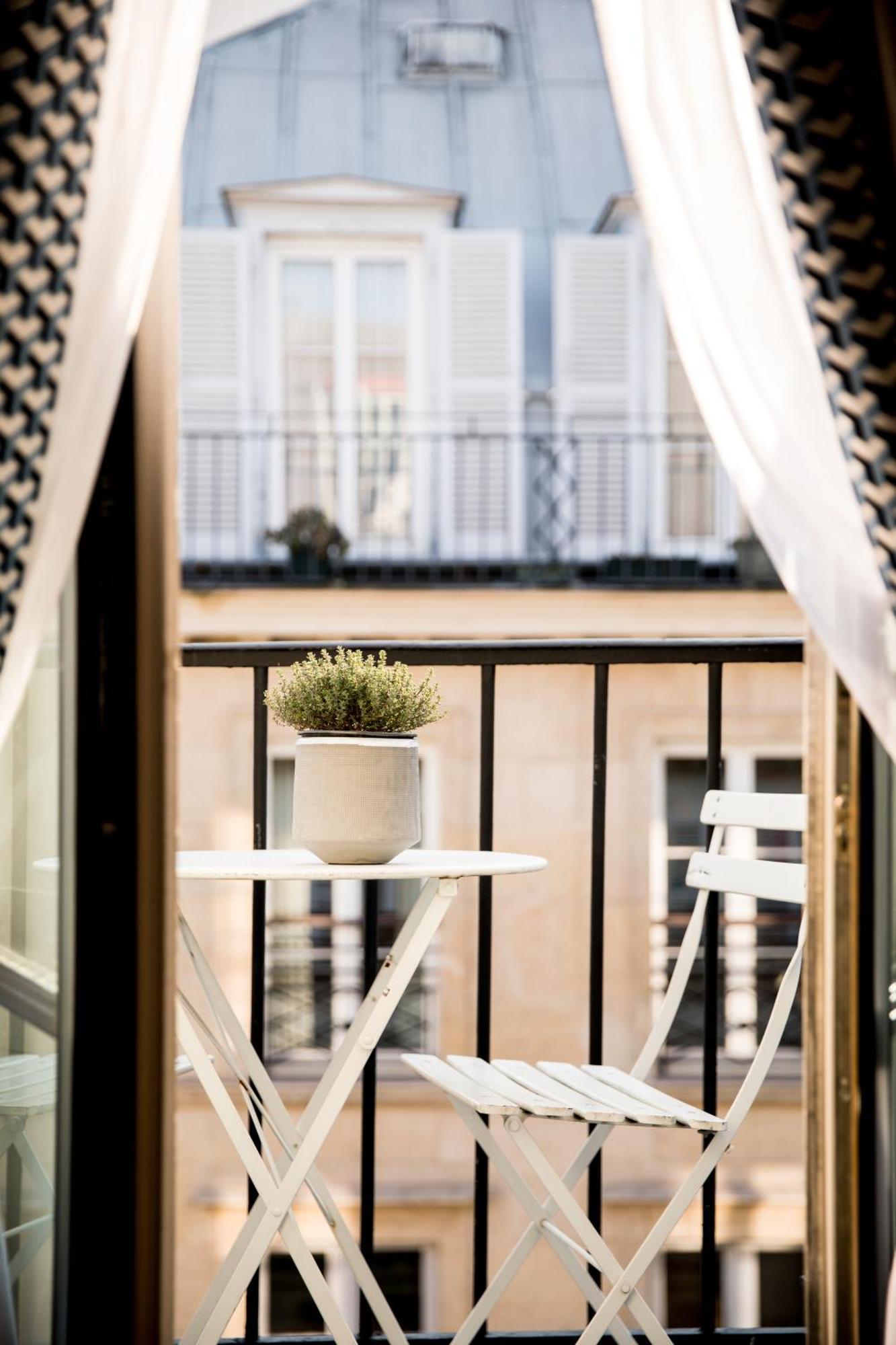 Habitación con cama grande, balcón y vistas a las azoteas de París